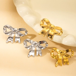 Boucles d'oreilles nœuds en acier titane poli, coloris or et argent, sur plateau