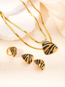 Detailed close-up of golden titanium jewelry set with black zebra print on textured stone