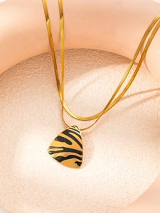 Detailed close-up of golden snake chain with a zebra-patterned triangle pendant