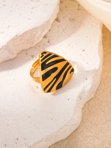 Detailed close-up of a gold triangle ring with black animal patterns on white stones