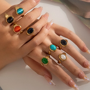 Detalle de anillos ajustables dorados con piedras ovales de colores en manos de mujer