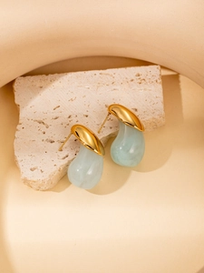 Detail of vintage gold drop earrings with light green resin waterdrop pendants on stone