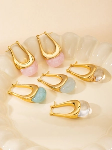 Detailed view of three pairs of gold U-shaped earrings with colorful mineral pendants