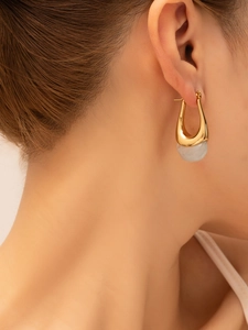 Detail view of U-shaped gold titanium earring with translucent white gemstone on model