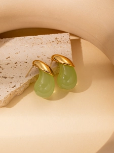 Detail of gold crescent stud earrings with translucent green teardrop resin pendants