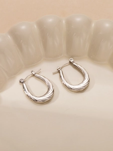 Macro di orecchini a tortiglione in argento con chiusura a U su piatto in ceramica crema