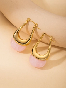 Detail of U-shaped gold earrings featuring pink translucent resin and polished metal texture