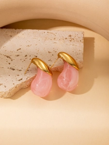 Detail of pink resin teardrop earrings with marble texture on beige travertine stone