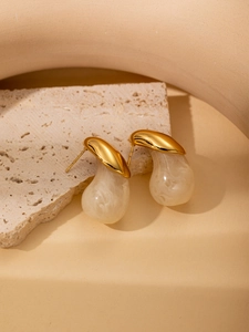 Detailed macro view of polished gold metal earrings with cream marble resin drop charms