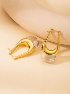 Macro shot of minimalist gold U-shaped earrings with a clear resin horseshoe design