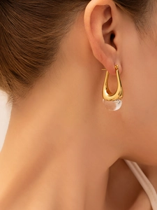 Close-up of elegant gold U-shaped earrings with a clear round pendant on model