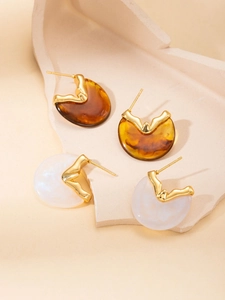 Detail of elegant amber resin and pearl white studs with wavy gold metal edges