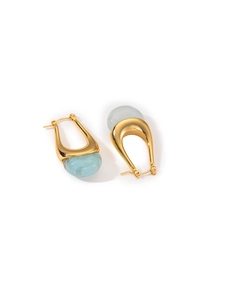 Detail view of gold titanium earrings featuring light blue translucent stone pendants