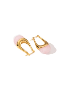 Detailed close-up of gold titanium steel U-shaped earrings with translucent pink gemstones