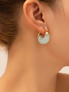 Close-up of elegant 18K gold-plated earring with translucent light blue stone detail