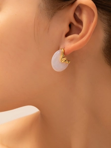 Close-up of minimalist gold titanium earrings with translucent resin inlay on female model