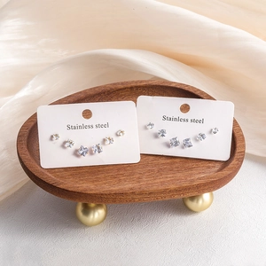 Gros plan de boucles d'oreilles carrées en zircon doré et argenté sur support bois