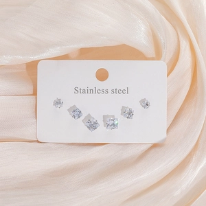 Détail de six boucles d'oreilles carrées en zircon et acier inoxydable sur fond de soie