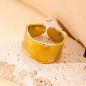 Macro shot of gold plated titanium steel ring with irregular wavy edges on stone