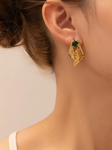 Close-up of vintage gold geometric stud earrings with green gemstone on model