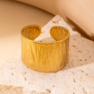 Macro detail of gold-plated stainless steel wide ring with unique vertical draped texture