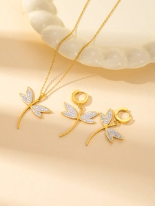 Detailed view of gold dragonfly jewelry set with white wings and sparkling crystals