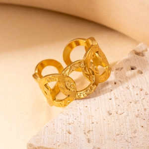 Macro detail of gold-plated stainless steel ring with overlapping C-shaped patterns