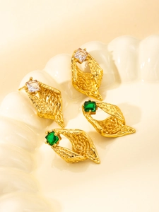 Macro detail of vintage gold titanium earrings with square emerald and clear crystals