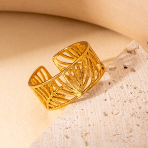 Detailed macro view of an adjustable gold-plated stainless steel ring with palm leaf texture