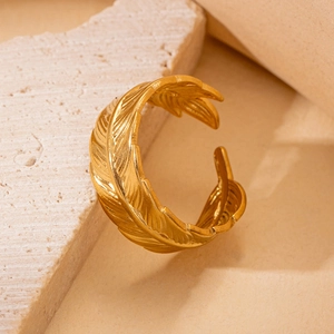 Detailed macro shot of a gold feather ring with vintage engravings on stone surface