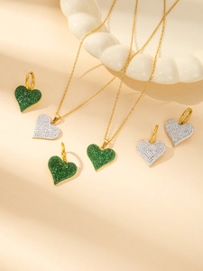 Macro shot of 18K gold plated heart necklace and earrings set with green gemstones