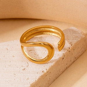 Detail of gold-plated double-layer wave ring on stone surface with textured finish