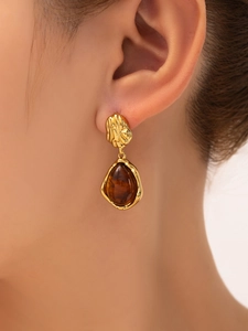 Detail view of vintage gold drop earrings with amber resin pendant on model's ear