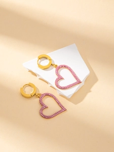 Detail of pink crystal heart earrings on stone stand with soft sunlight shadows