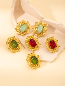Detail view of vintage gold plated earrings with colorful gemstones on a stone base
