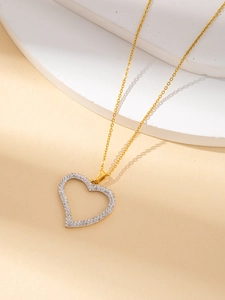 Close-up of heart-shaped pendant with pavé crystals on a delicate gold chain necklace