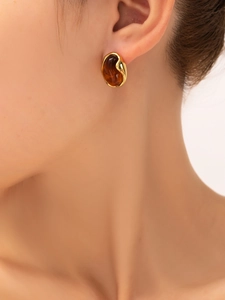 Detailed close-up of a model wearing retro gold titanium earrings with amber resin stones