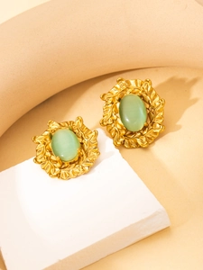 Detail view of vintage gold earrings with oval green stones and leaf-textured metal edges