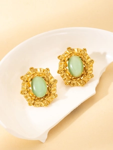Macro detail of gold-plated titanium earrings featuring green opal and leaf texture