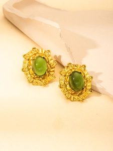 Macro detail of vintage gold stud earrings with oval green stone and textured metal edge