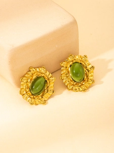 Macro detail of vintage gold-plated stud earrings with oval green stone and leaf texture
