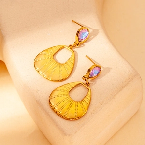 Detailed shot of gold drop earrings with teardrop crystals and textured metal pendants