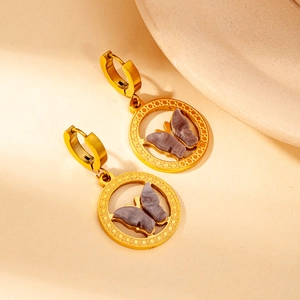 Close-up of 18K gold plated butterfly drop earrings with marble texture on beige background
