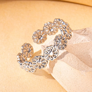 Detailed macro view of adjustable silver daisy petal ring on beige stone display