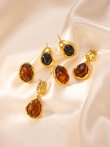 Detail of vintage gold plated earrings with amber resin on creamy satin fabric