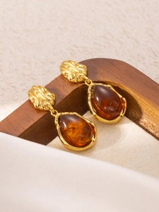 Detailed close-up of vintage gold titanium earrings with teardrop amber resin charms