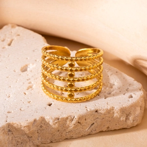 Detail eines goldenen mehrlagigen offenen Rings mit Perlenstruktur auf Steinhintergrund