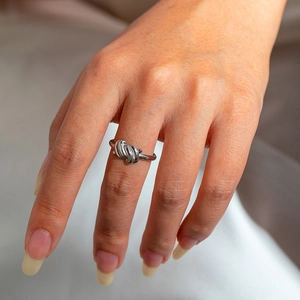 Close-up of a silver twisted knot ring set on finger with a minimalist layered design