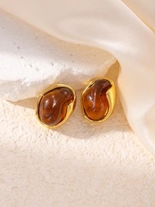Macro detail of organic amber resin earrings with gold metallic edges on a stone