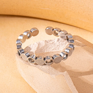Detail of matte silver titanium steel ring with geometric circles on stone surface